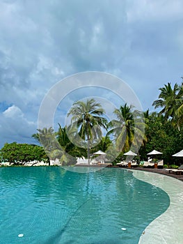 Outdoor tourism landscape. Luxurious beach resort with swimming pool palm trees and blue sky.