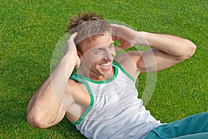 Outdoor training. Young man doing sit-ups