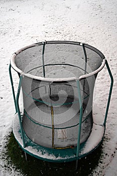 Outdoor trampoline in winter on a snow covered meadow. It can have symbolic or metaphoric meaning.