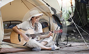 Outdoor travel activity with Millennials female in safari clothes playing a guitar.