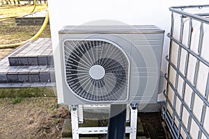 Outdoor unit of a low-power air heat pump located in front of the house.