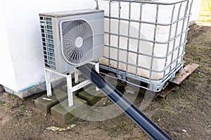 Outdoor unit of a low-power air heat pump located in front of the house.