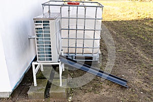 Outdoor unit of a low-power air heat pump located in front of the house.