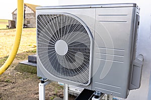 Outdoor unit of a low-power air heat pump located in front of the house.