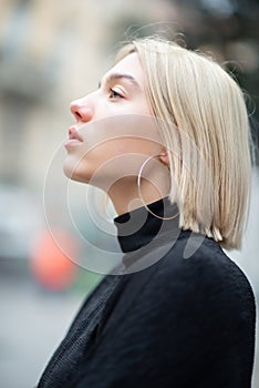 Outdoor urban female portrait in profile. Fashion model. Young woman posing in Milan streets. Beautiful caucasian girl with blond