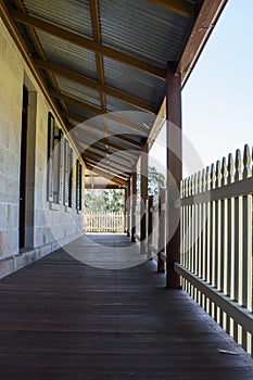 Outdoor verandah patio deck of sandstone brick cottage with picket fence in sunshine