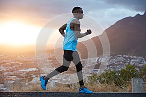 Outdoor view of active young male jogger covers long destiantion ealy in morning at dawn, runs over mountains view, has