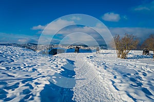 Outdoor view of antiaircraft gun over the snow with a city building behind in Trondheim