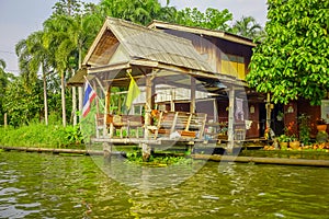 Outdoor view of floating poor house with two falgs at the enter of the building on the Chao Phraya river. Thailand
