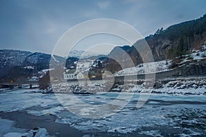 Outdoor view of frozen river with some wooden houses at one side of the road at Gol Mountain Are