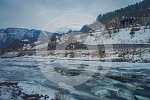 Outdoor view of frozen river with some wooden houses at one side of the road at Gol Mountain Are