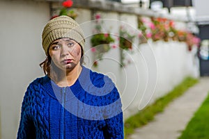 Outdoor view of homeless woman begging on the street in cold autumn weather wearing a blue hoodie at sidewalk