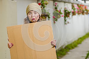 Outdoor view of homeless woman holding up blank cardboard sign