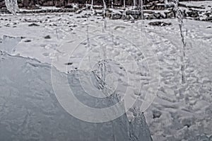 outdoor view of ice blocks at frozen water in winter texture with light white snow covering chunks of cracked ice on a frozen wint