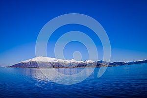 Outdoor view of mountain range in Norway. The beautiful mountain covered partial with snow in Hurtigruten region in