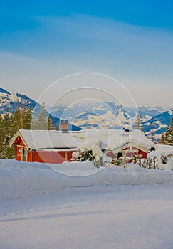 Outdoor view of red wooden typical housecovered with snow in the roof in GOL