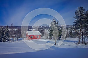 Outdoor view of red wooden typical housecovered with snow in the roof in GOL