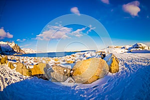 Outdoor view of snow melting over a rock at seaside at outdoors in snowy winter in the Arctic Circle