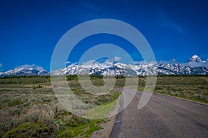 Outdoor view of stoned highway leading to the Grand Teton National Park, Wyoming, in a gorgeous sunny day with mountains