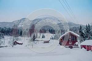Outdoor view of traditional Norwegian mountain red houses of wood covered with snow in stunning nature background in