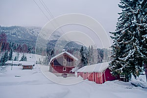 Outdoor view of traditional Norwegian mountain red houses of wood covered with snow in stunning nature background in