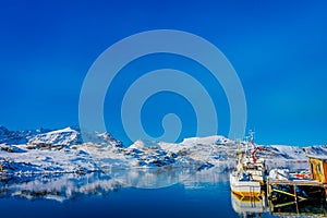 Outdoor view of two fishing boats in the port with mountain reflecting in the water on Lofoten islands