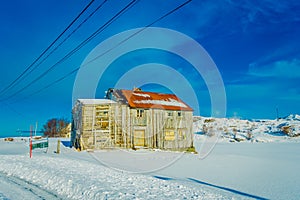 Outdoor view of very old wooden house partial covered with snow in Lofoten islands