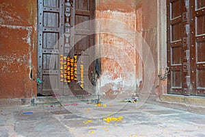 Outdoor view of a wooden door with some yellow flowers hanging, in a old house, in Agra city near of Taj Mahal in India