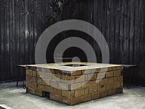 An outdoor vintage brick fireplace with bench on wood plank wall background