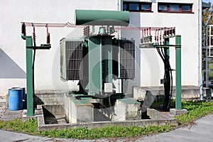 Outdoor vintage old high voltage transformer with multiple connected electrical wires at local electricity substation building