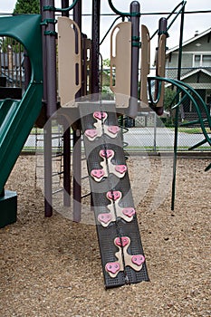 Outdoor wall climbing grips and wall going up the playground structure. Exercise, fitness, problem solving and fun