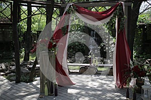 Outdoor wedding arch decorated with red and white fabric and red flowers