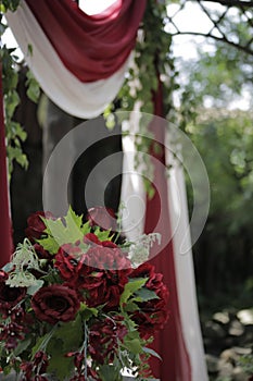 Outdoor wedding arch decorated with red and white fabric and red flowers