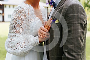 Outdoor wedding ceremony, close-up of the bride and groom hugging, holding hands with wedding rings.