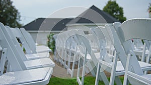 Outdoor wedding ceremony decoration before reception, decorated white chairs on the grass. Move camera
