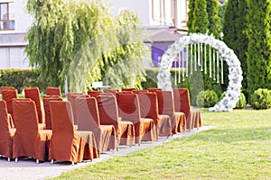 Outdoor wedding ceremony. Elegant decoration of a wedding ceremony outdoors. Outdoor wedding ceremony with brown chairs