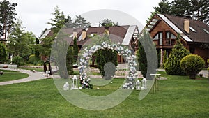 Outdoor wedding ceremony with a stunning floral arch and white chairs set in a serene garden