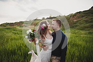 Outdoor wedding ceremony, stylish happy smiling groom and bride are hugging and looking at each other. The moment before kiss