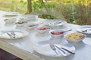 Outdoor white vintage table set for breakfast with empty plates ready for eating