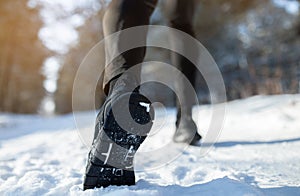 Outdoor winter activities. Male athlete in sports shoes jogging at park on snowy winter day, closeup view. Copy space