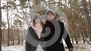 Outdoor winter forest shot of young wedding couple walking and having fun holding hands in snow weather pine forest