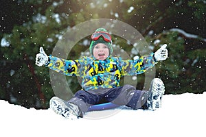 Boy sledding in a snowy forest. Outdoor winter fun for Christmas vacation. photo
