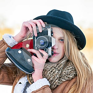 Outdoor winter lifestyle portrait of pretty blonde woman with retro camera