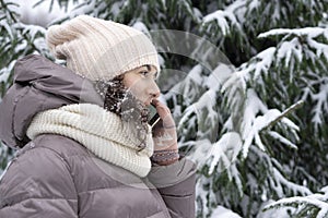 Outdoor winter portrait. Beautiful woman 45 years old talking on a cell phone in a snowy winter park