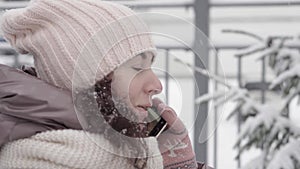 Outdoor winter portrait. Beautiful woman 45 years old talking on a cell phone in a snowy winter park