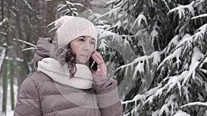 Outdoor winter portrait. Beautiful woman 45 years old talking on a cell phone in a snowy winter park