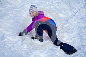 Outdoor winter portrait of little cute girl wearing ski clothes. Girl climbing a snow slide.