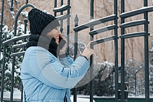 Outdoor winter portrait of mature woman with mobile phone on snowy city street, woman smiling talking