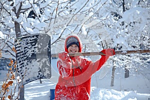 Outdoor winter portrait of a small healthy happy child with a shovel in hand.