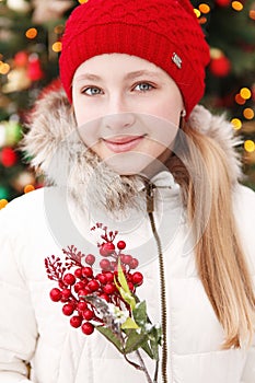 Outdoor winter young blonde teen girl portrait. At background blurred christmas tree.